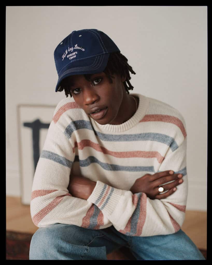Young man wearing a striped sweater and blue cap in NYC.