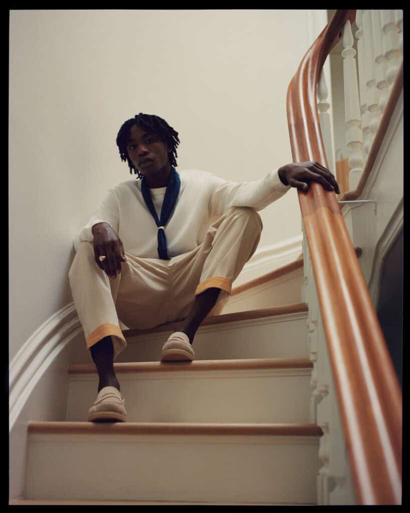 Fashion model sitting on staircase in ZARA MAN NYC 2021 collection.