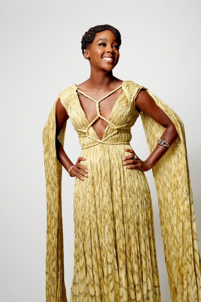 Elegant woman in gold gown with cape at Critic's Choice Awards.