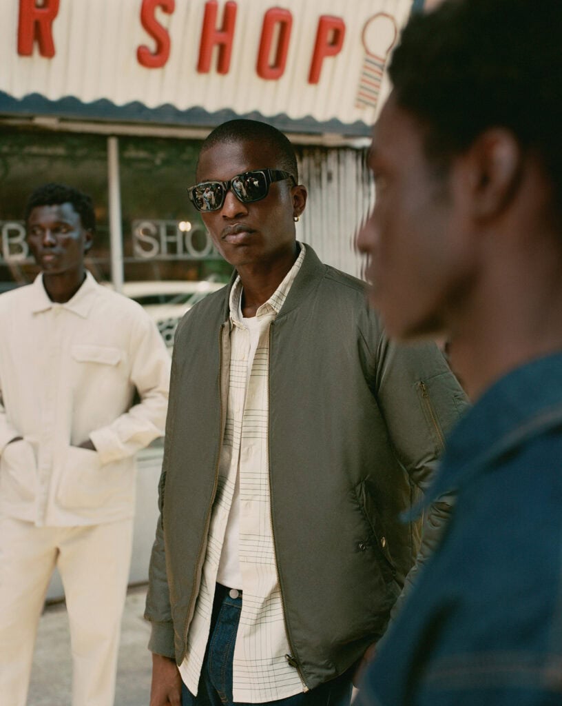 Stylish man wearing sunglasses and a bomber jacket in Brooklyn, NY.