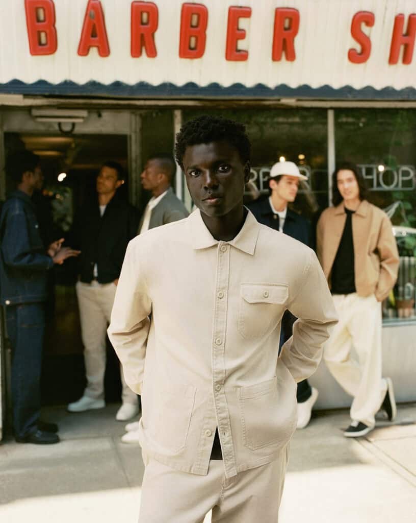 ZARA MAN model in Brooklyn, 2022, showcasing stylish men's fashion outside a barber shop.