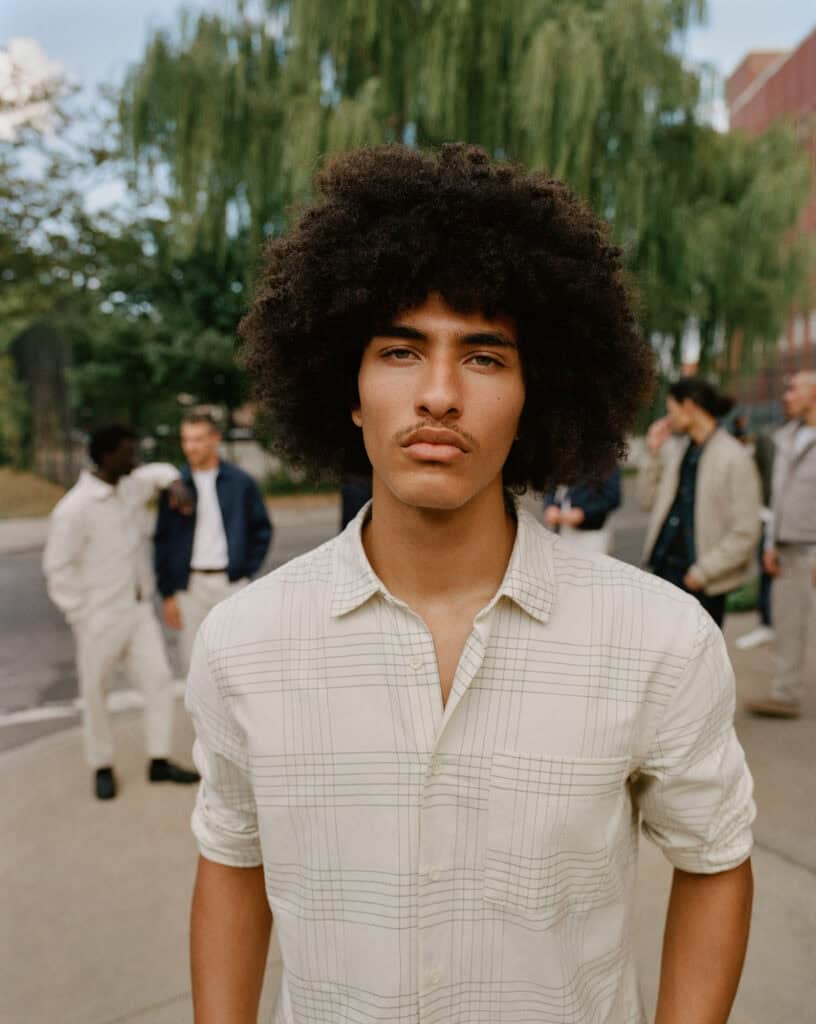 Young man with curly hair posing outdoors in Brooklyn, 2022.