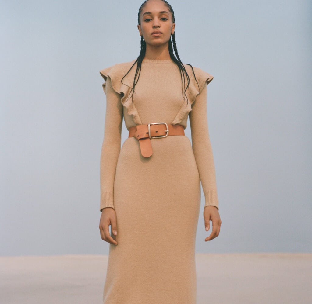 Elegant beige dress with ruffled shoulders and a wide belt, embodying modern femininity.