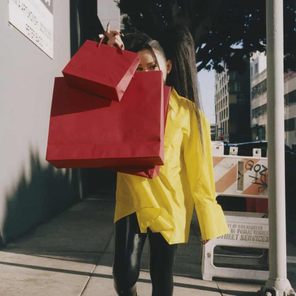 Bella Poach holding shopping bags in street scene.