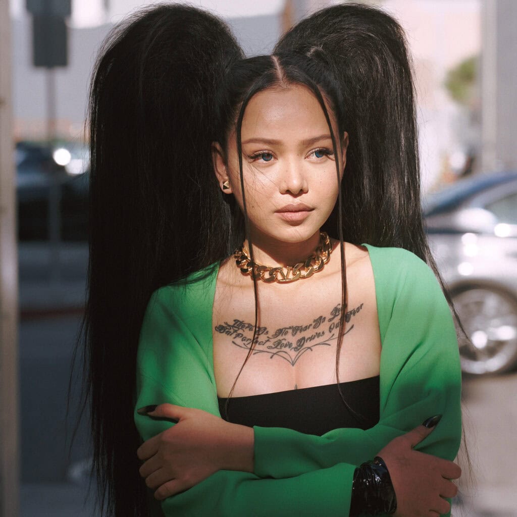 Bella Poach wearing green jacket with bold makeup and jewelry at Perfect Magazine shoot.