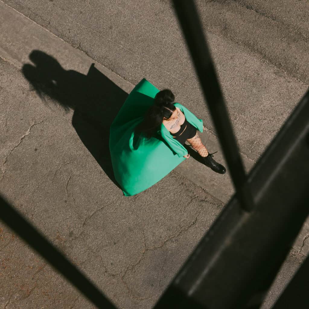 Forward image of Bella Poarch wearing a striking green coat, captured from above on an urban street.