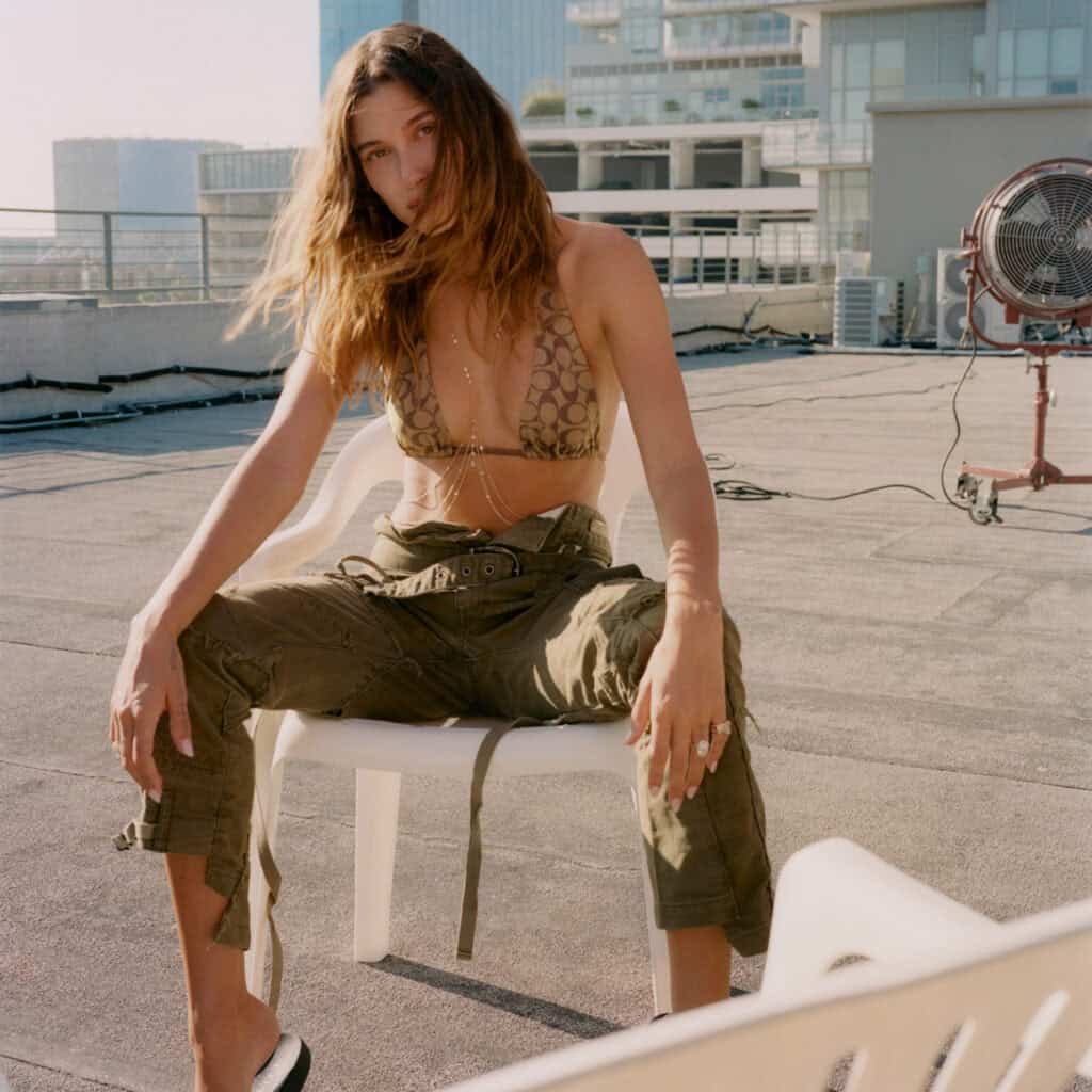 Hailey Bieber sitting on rooftop in casual outfit for Perfect Magazine.