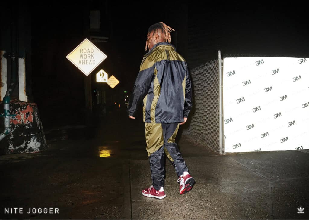 Man wearing ADIDAS Nite Jogger shoes walking at night in urban setting.