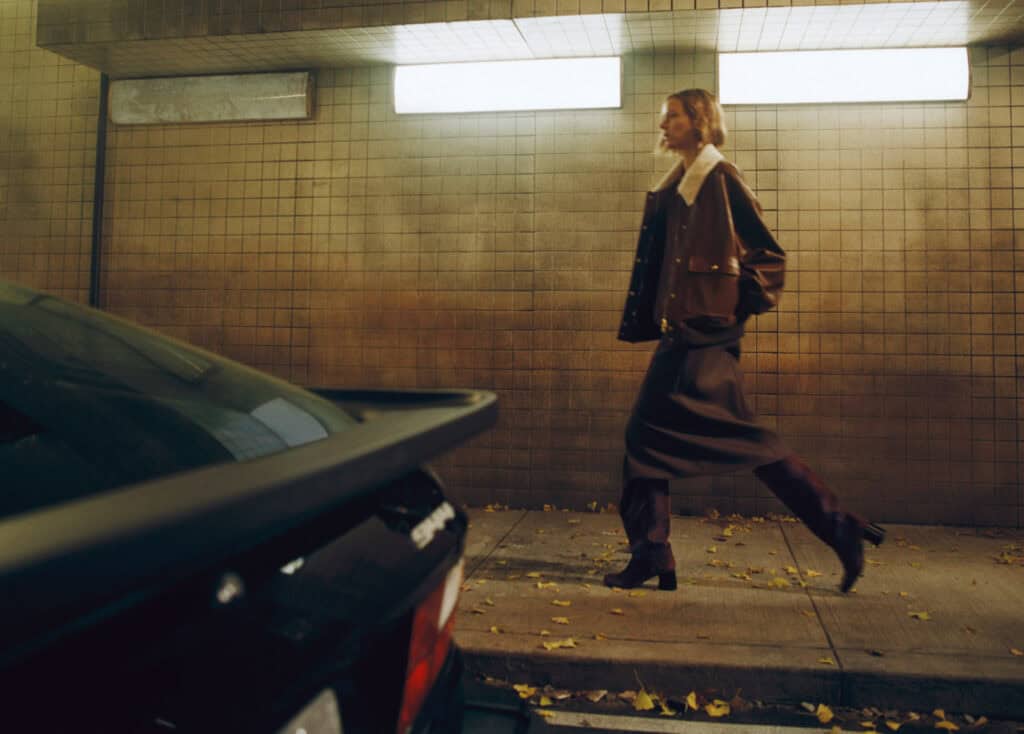 Fashion model walking in urban parking garage, showcasing KHAITE Freja 2022 collection.