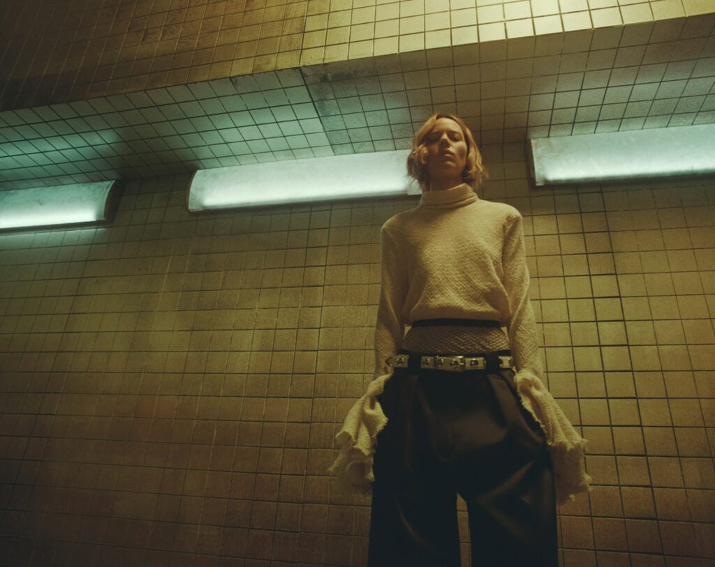 Model wearing KHAITE Freja 2022 outfit in urban subway setting.