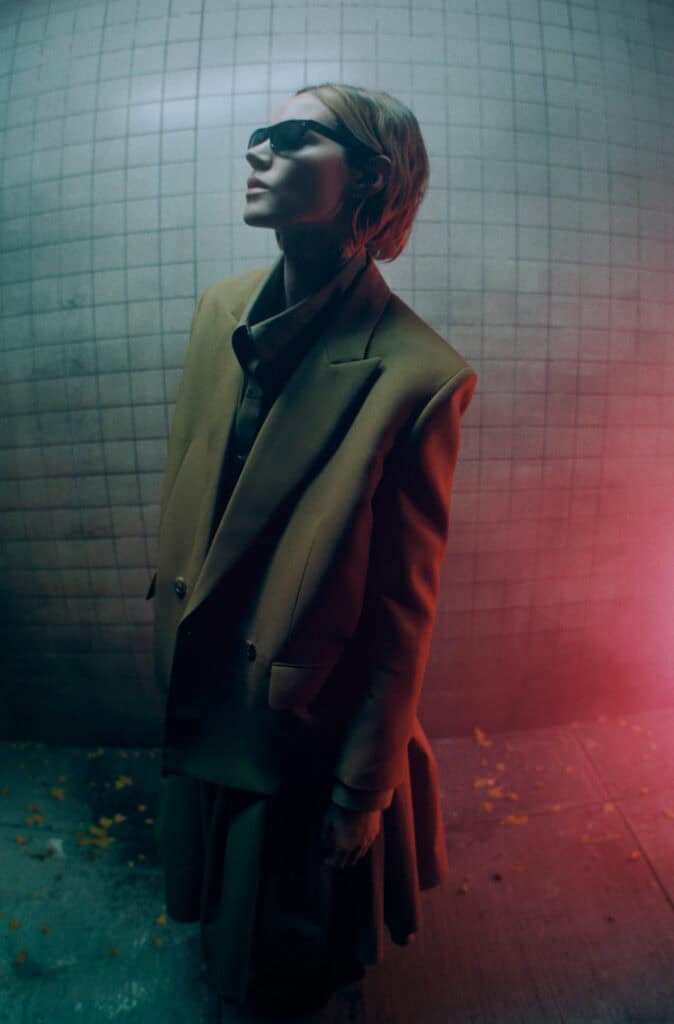 Woman in oversized blazer and sunglasses in urban setting, fashion photo.