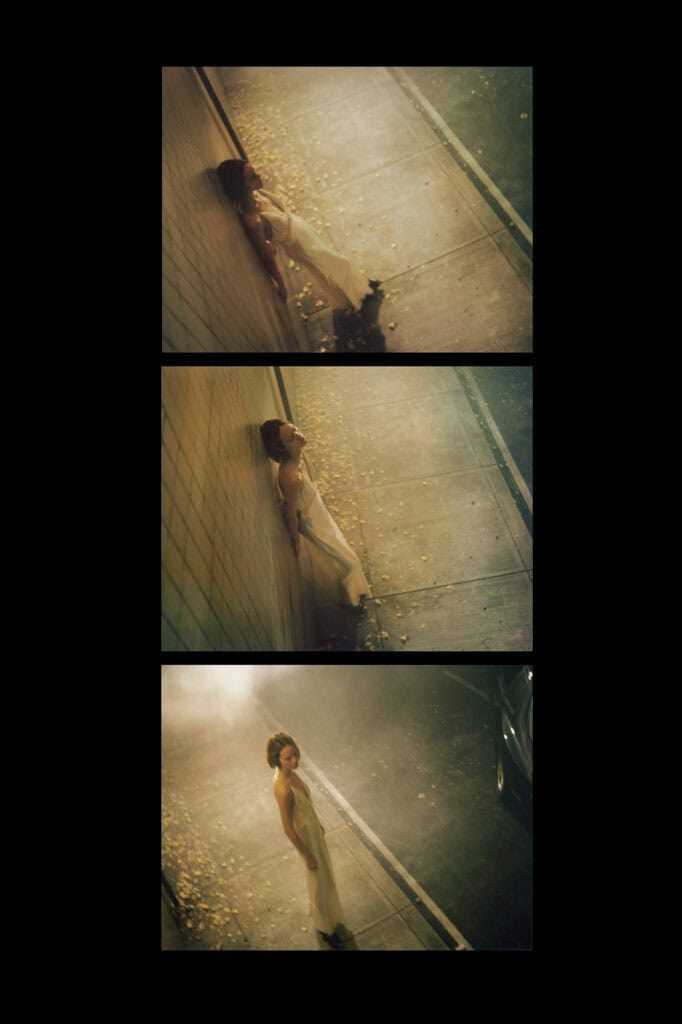 Woman lying on the sidewalk at night with falling leaves and streetlights.