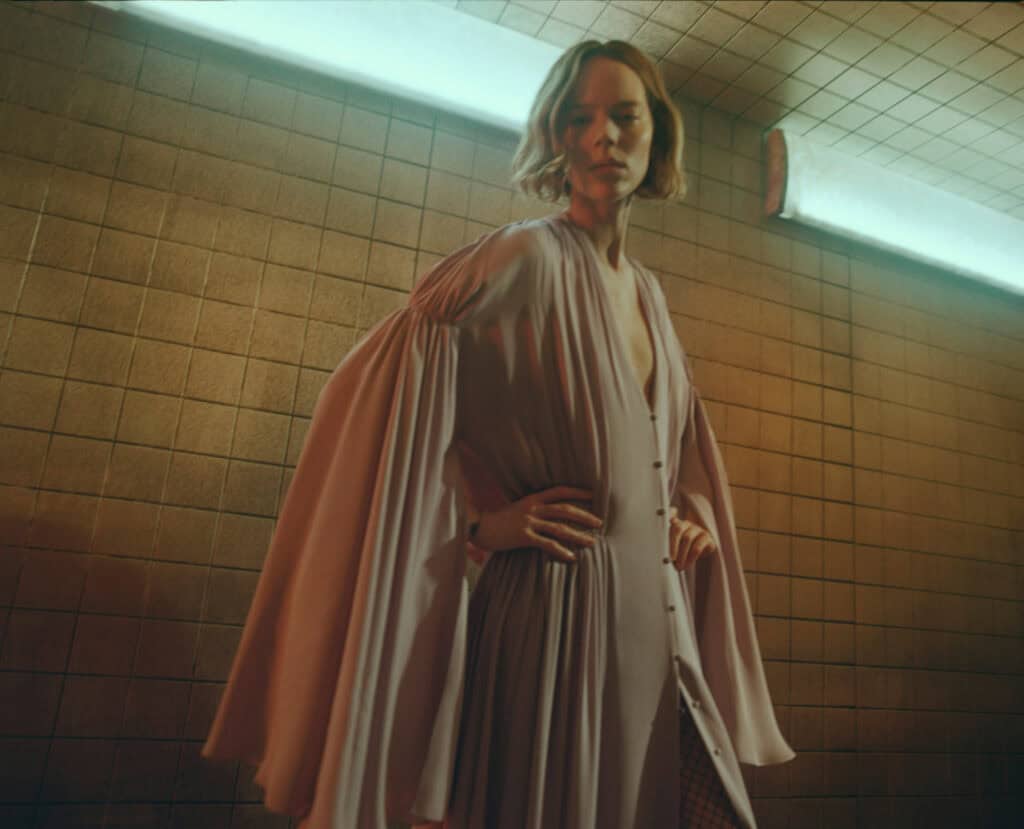 Fashion model wearing KHAITE Freja 2022 beige dress in urban setting.