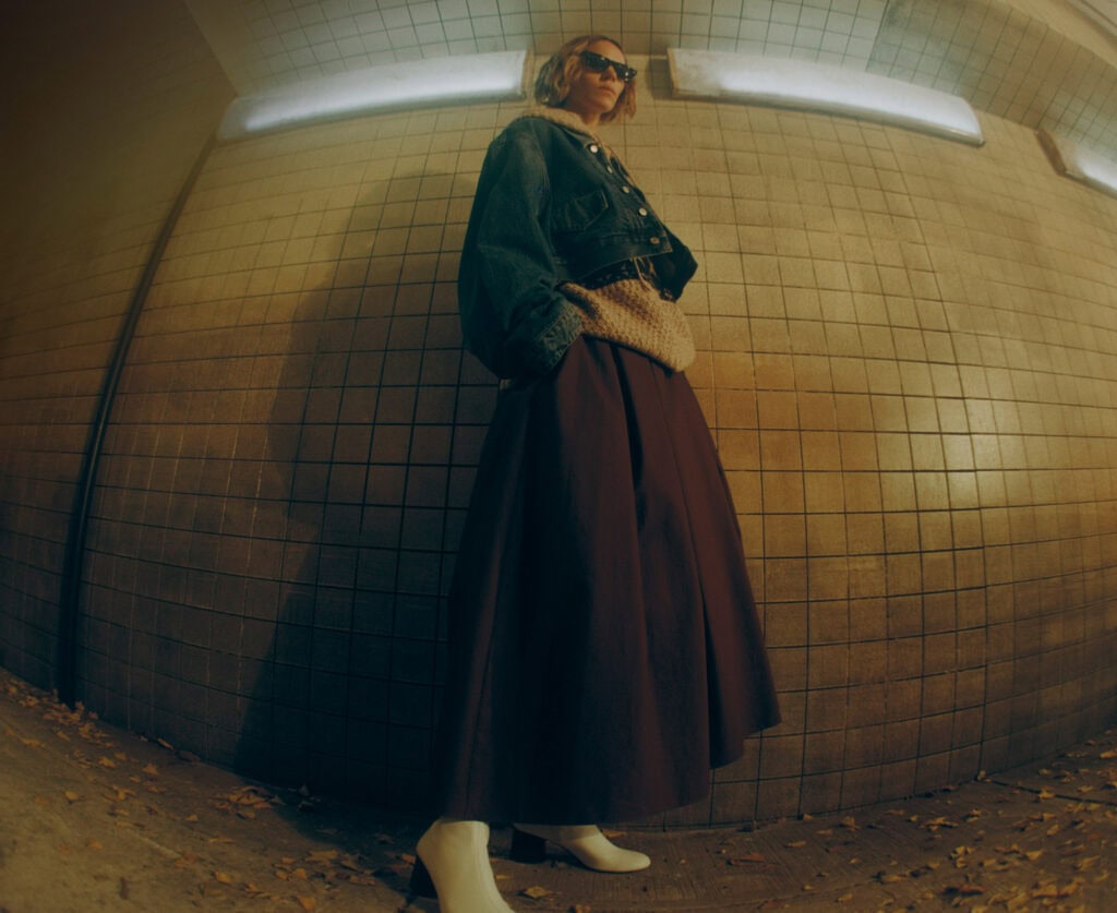 Stylish woman in KHAITE Freja 2022 outfit at subway station.