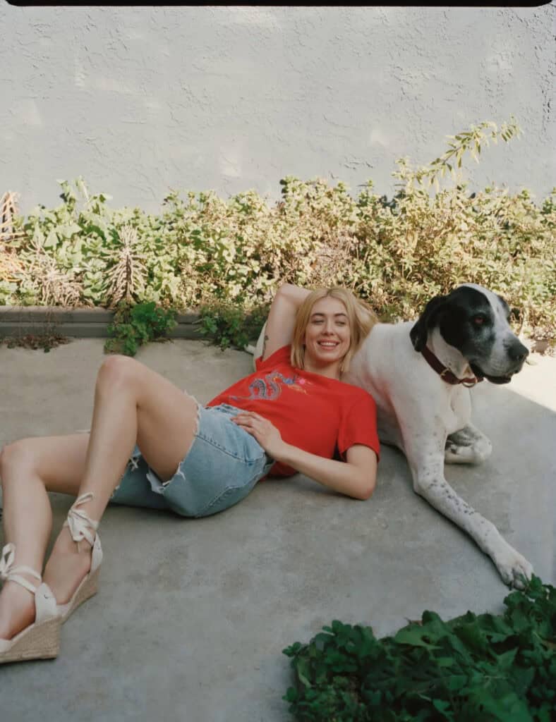Relaxed woman lying on the ground with her large dog outdoors in Los Angeles.