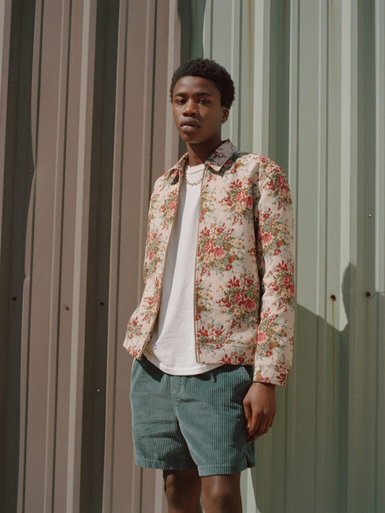 Urban Outfitters desert-inspired fashion photo with a young man in floral jacket and shorts.