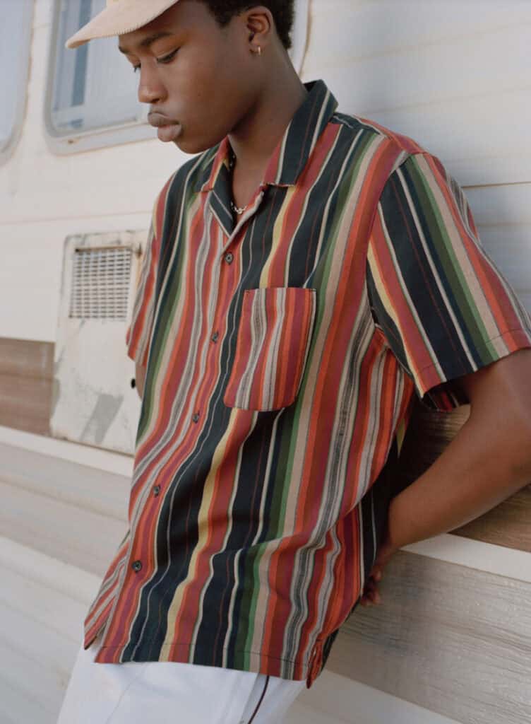 Young man wearing a colorful striped desert-inspired shirt outdoors.