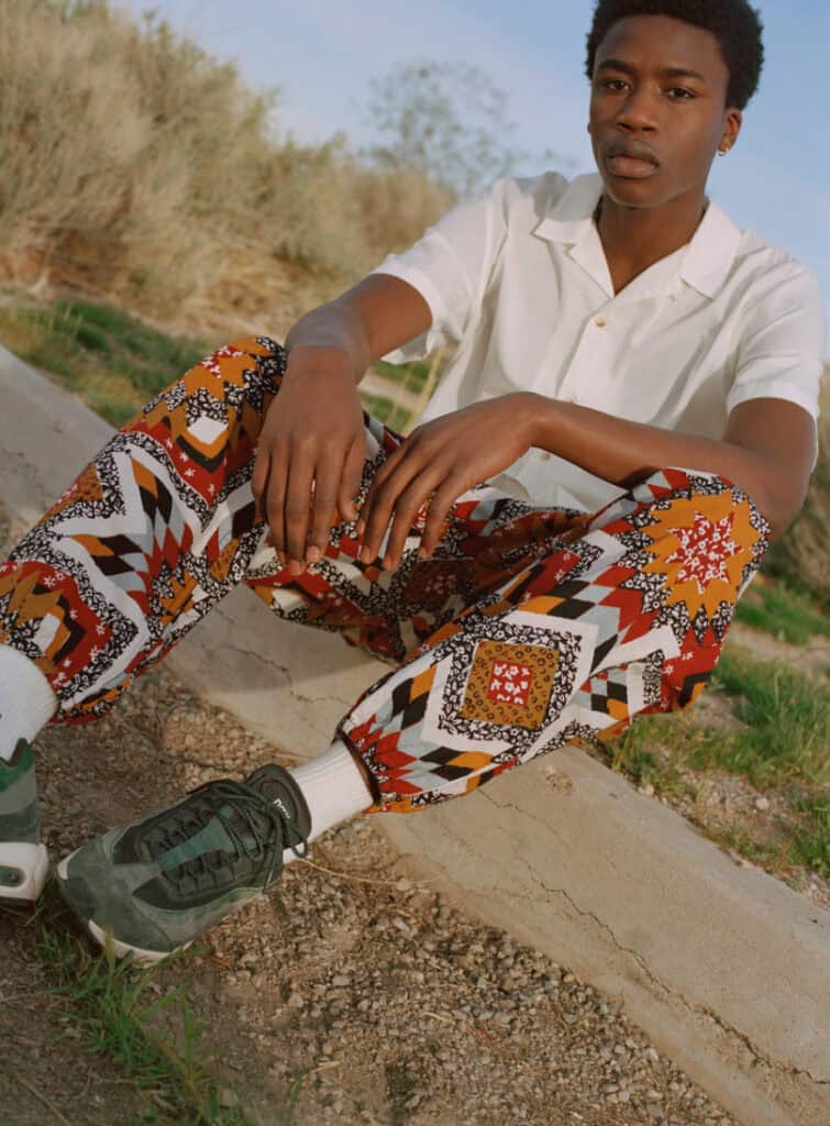 Urban Outfitters desert fashion with vibrant patterned pants and casual white shirt.