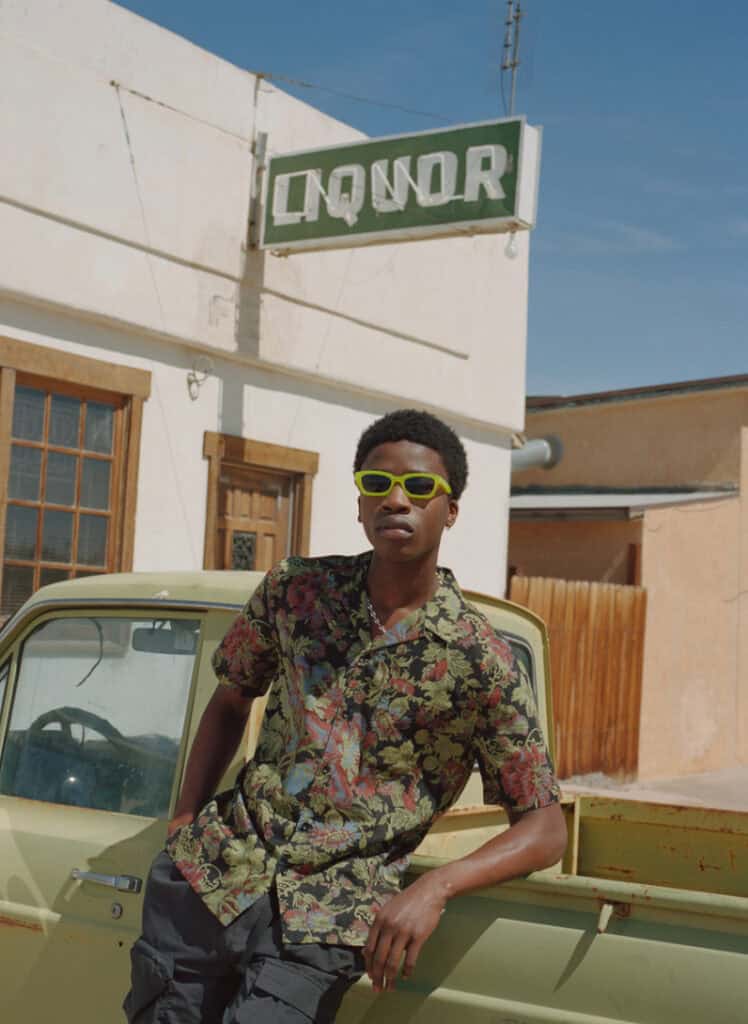 Urban Outfitters desert scene with model in floral shirt and sunglasses.