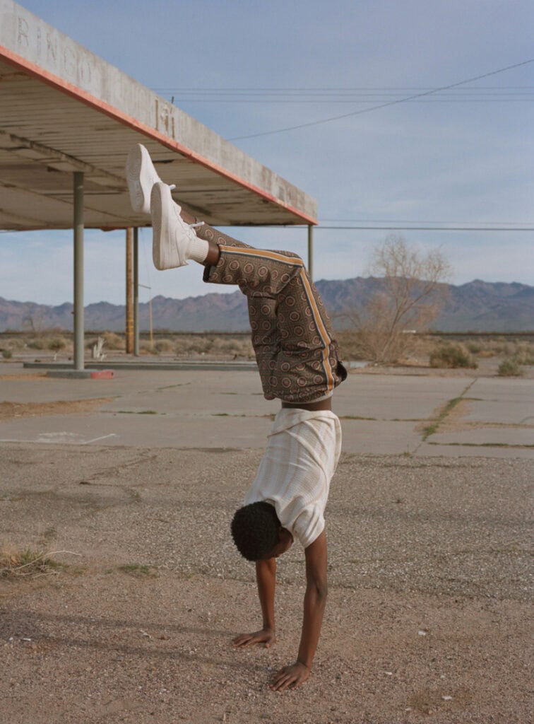 Person performing a handstand outdoors in a desert landscape.