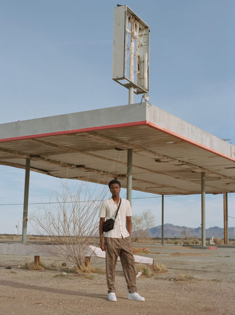 Urban Outfitters desert scene, 2019, with a young man standing in front of an abandoned gas station.