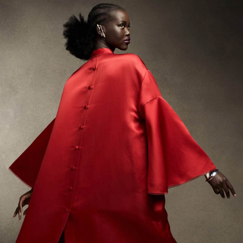 Stylish model wearing a striking red gown with voluminous sleeves and sleek design.