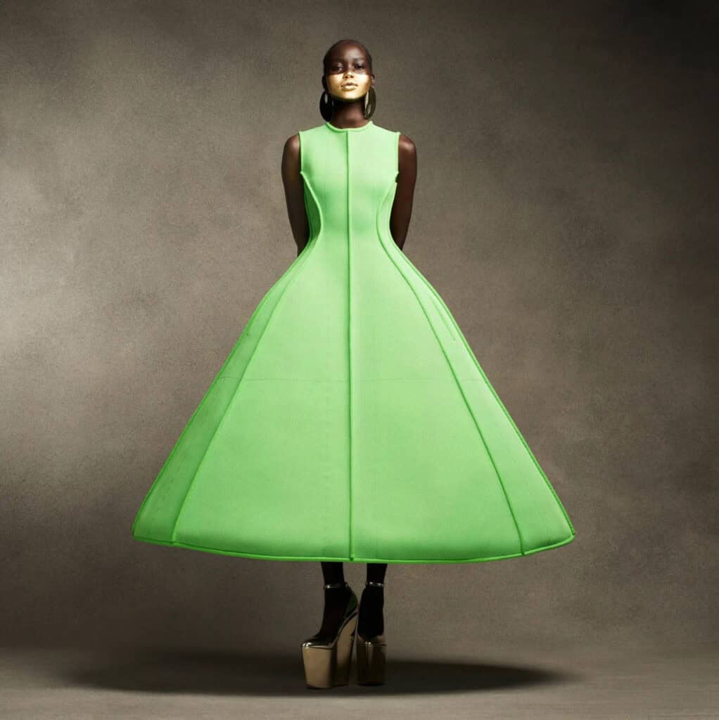 Model in vibrant green dress with exaggerated proportions for Vogue shoot.