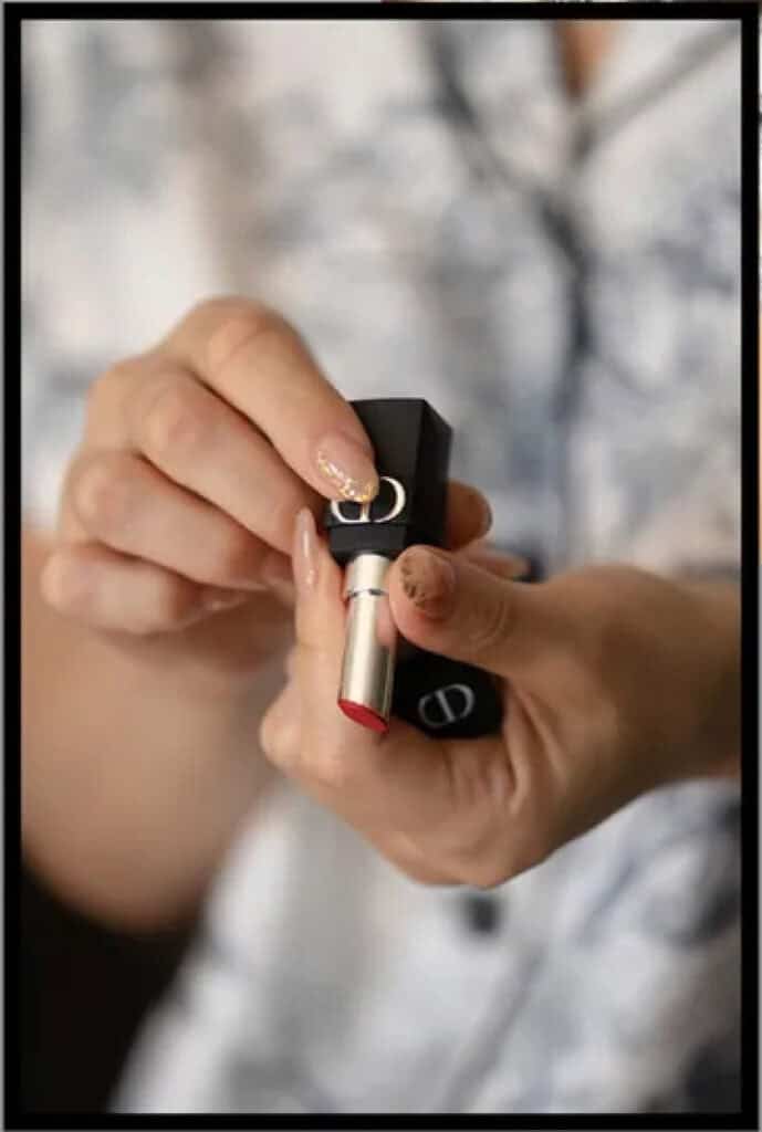 Close-up of Dior lipstick being applied by hand at a beauty event.