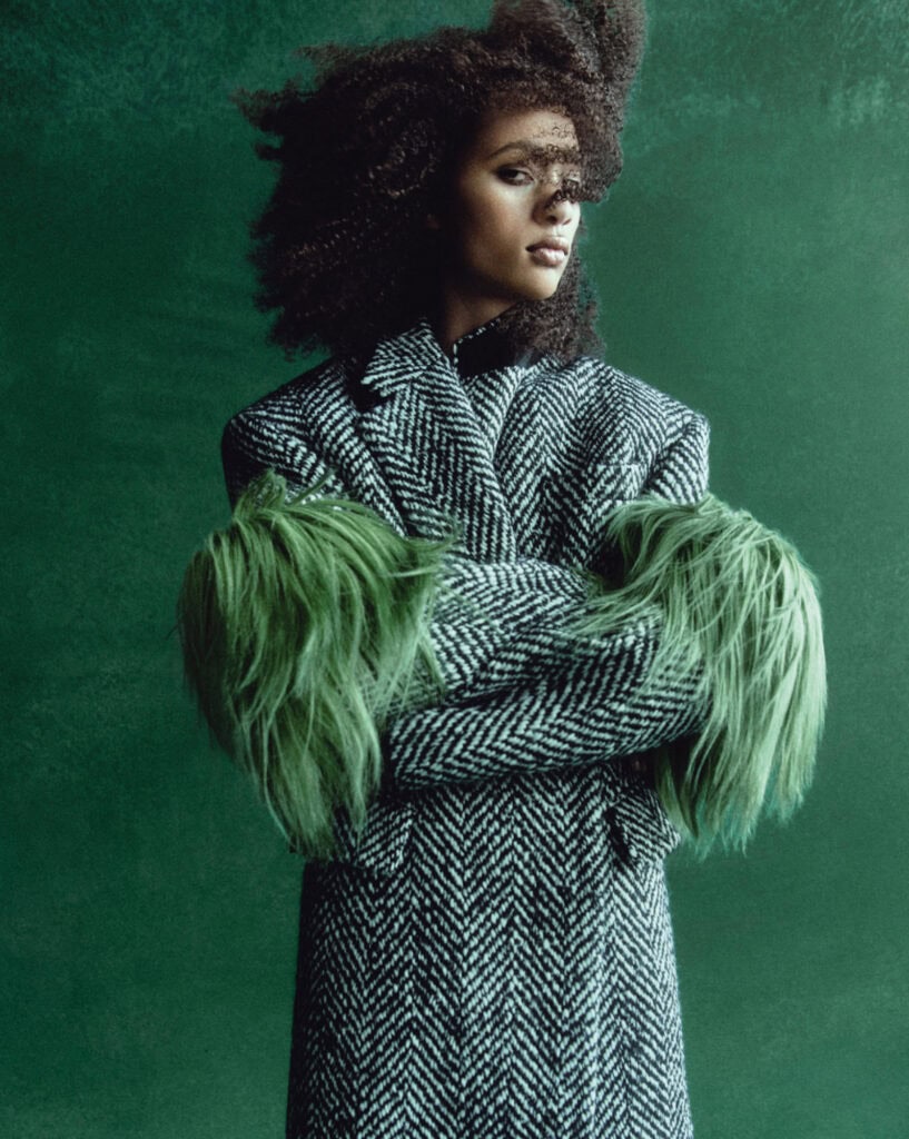 Fashion portrait of Selena Forrest in bold outfit with green feathered sleeves.