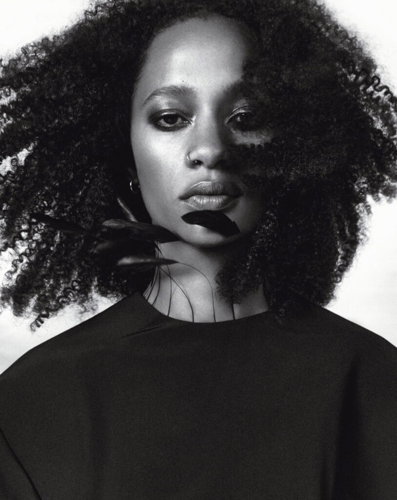 Black and white portrait of Selena Forrest with natural curly hair and intense gaze.