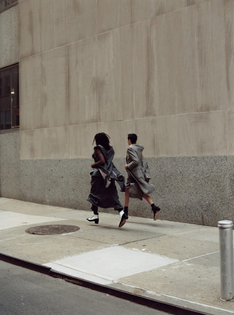 Urban street scene with two stylish individuals walking briskly.