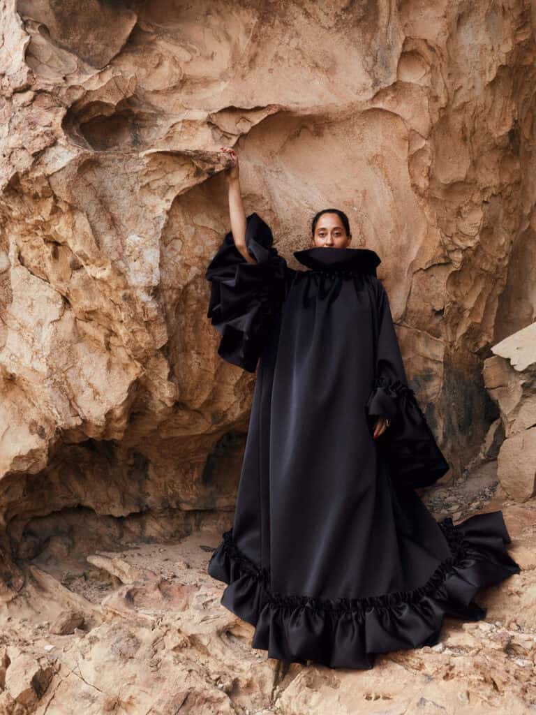 Tracee Ellis Ross in a dramatic black gown at a rocky outdoor location.