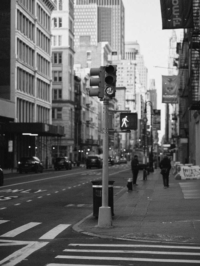 Urban city street scene in black and white, featuring traffic lights and pedestrians in New York Cit.