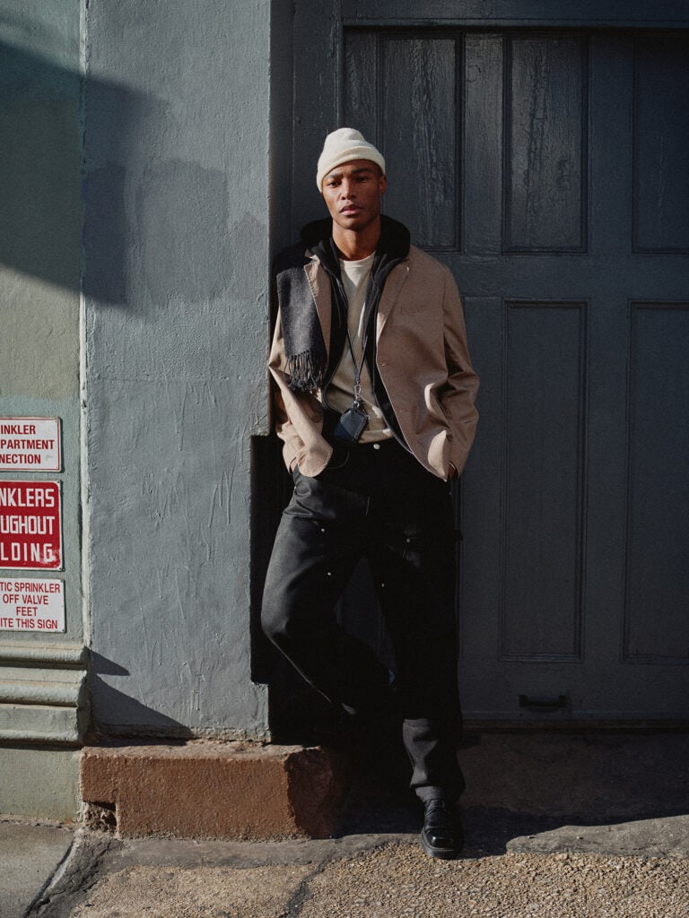 Young male model in stylish winter outfit standing outside in New York City, urban fashion scene.