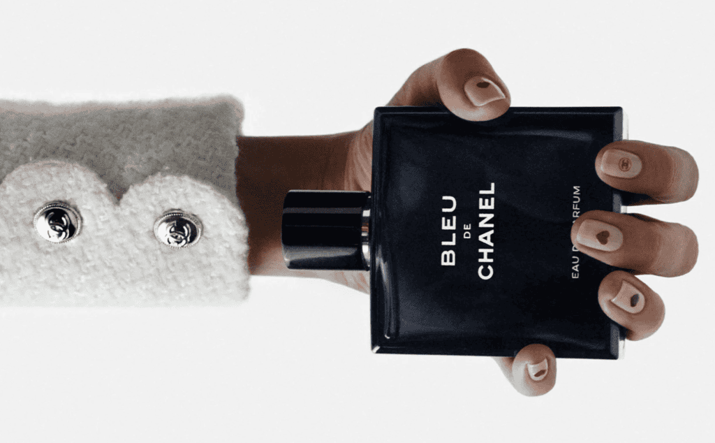 Hand holding Chanel Bleu perfume bottle for Valentine's Day 2024.