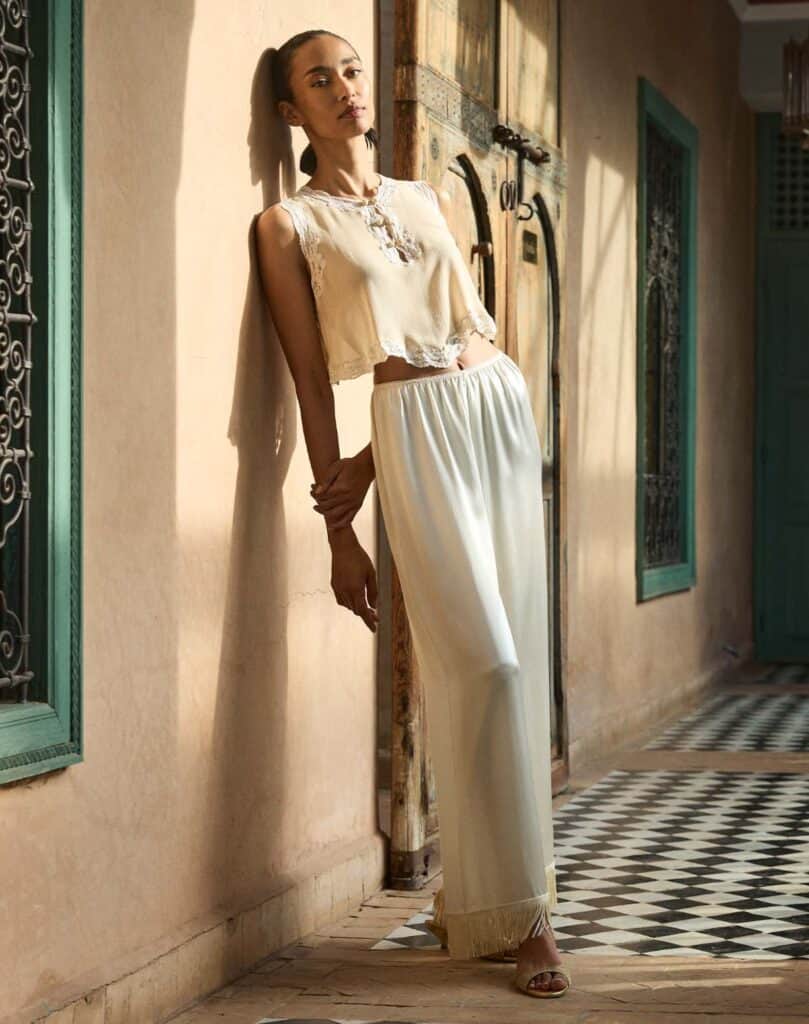 Woman in Moroccan-inspired outfit standing indoors with traditional decor.
