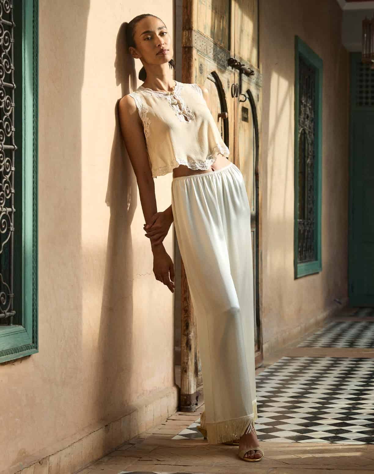 Woman in Moroccan-inspired outfit standing indoors with traditional decor.