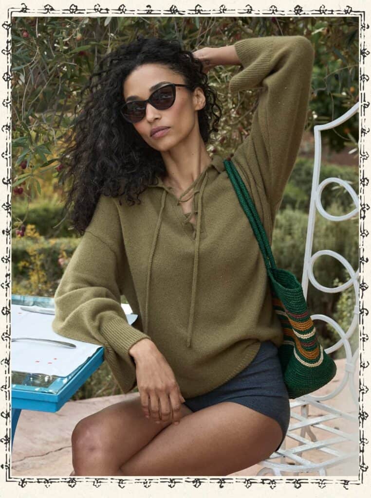 Woman in sunglasses and hoodie sitting outdoors in Morocco.