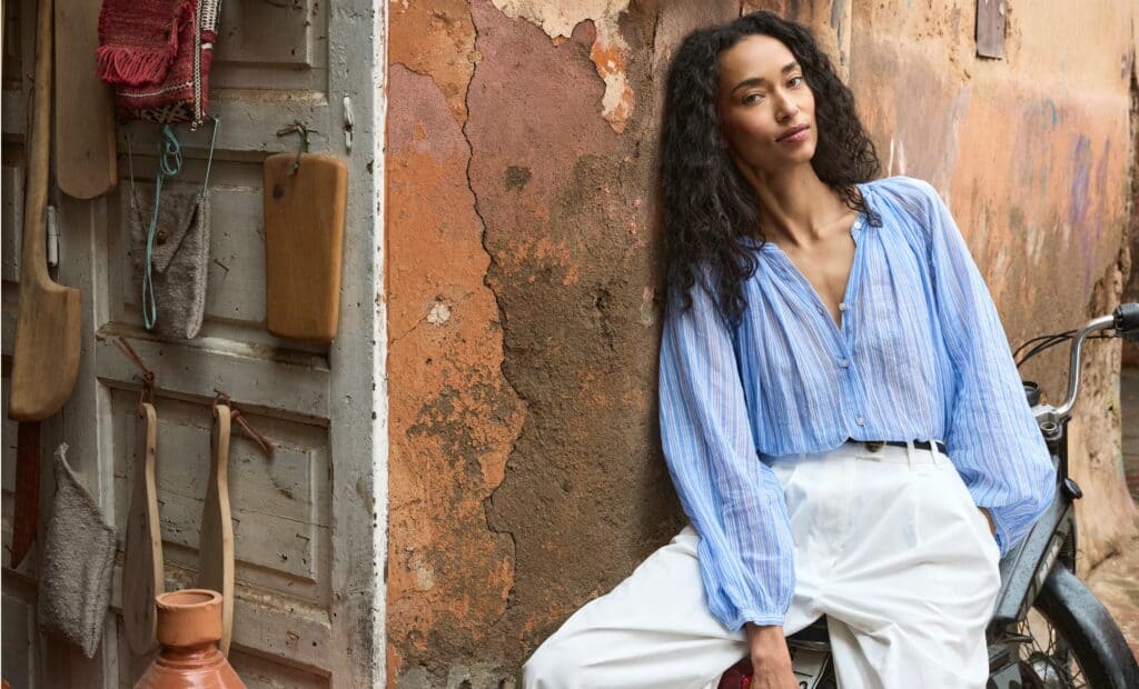 Stylish woman in blue blouse and white pants in Morocco setting.
